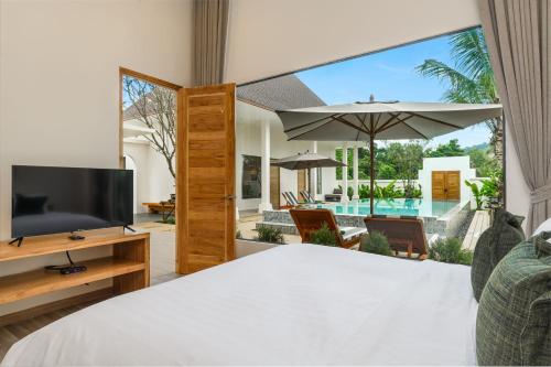 a bedroom with a bed and a tv and a patio at Dutch Villas Phuket in Koh Lone