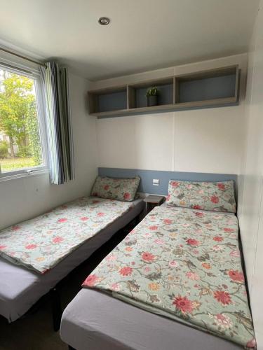 a bedroom with two beds and a window at Nordseechalet direkt am Lauwersmeer - Fußläufig zur Nordsee! Siblu Lauwersoog! Familienpark in Lauwersoog