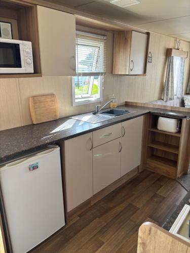 a small kitchen with a sink and a microwave at 27 Ivy Close in Mablethorpe