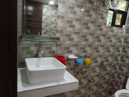 a bathroom with a sink and a tiled wall at Nodir Neer - Nest by the River in Fatepur