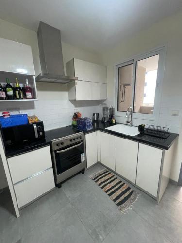 a kitchen with white cabinets and a stove and a sink at Perf Deluxe in Accra