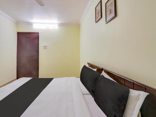a bedroom with a bed and a brown door at Hotel O SS ELITE in Karīmnagar