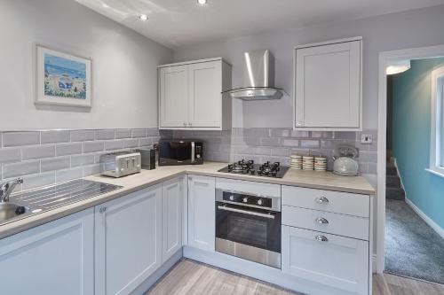 a kitchen with white cabinets and a stove top oven at Seaside Retreat 2Bed Apartment Central Saltburn in Saltburn-by-the-Sea