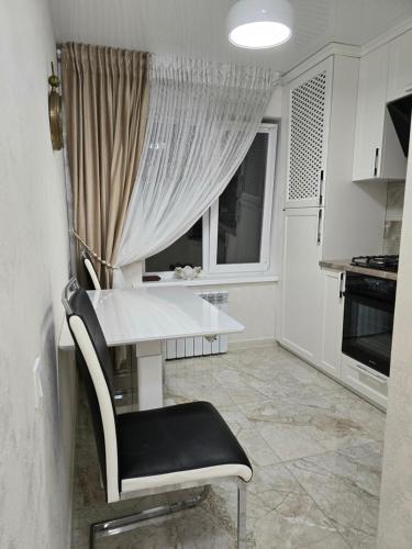 biała kuchnia ze stołem i oknem w obiekcie VIP Квартира в центре Бендер улица Кирова 36 w mieście Bender