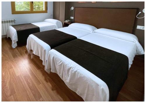 two beds in a hotel room with white and black sheets at Hotel San Lázaro in Santiago de Compostela