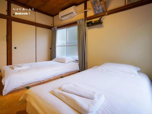 two beds in a room with a window at 7時IN19時OUT # 池袋王子赤羽駅無料送迎# 上野駅14分 # 日暮里駅10分 # 一棟貸切 # 最大7名 # B # 7 00 IN19 00 OUT # Free pick up Ikebukuro Oji and Akabane Stations # 14 min to Ueno # 10 min to Nippori # Whole house rental # Max 7 # B in Tokyo