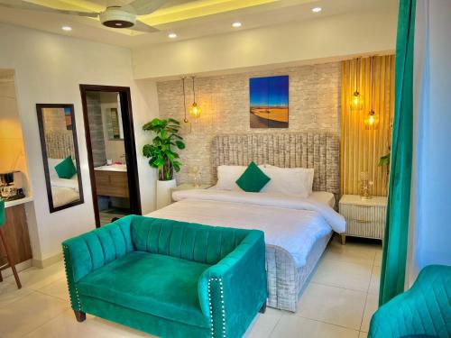 a bedroom with a large bed and a green couch at Skyline Hotel Apartments-Elysium Tower Facing Centaurus Mall Islamabad in Islamabad