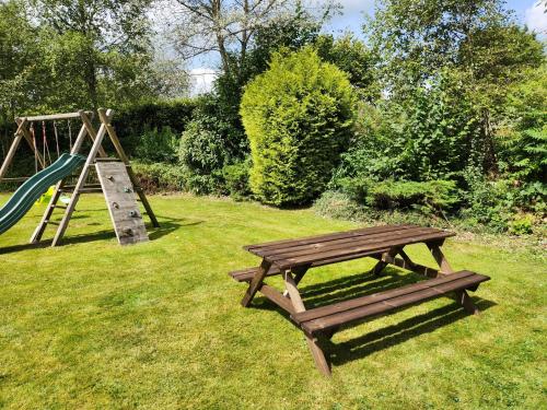 a wooden bench next to a playground with a slide at Gîte La Borbotte in Malmedy