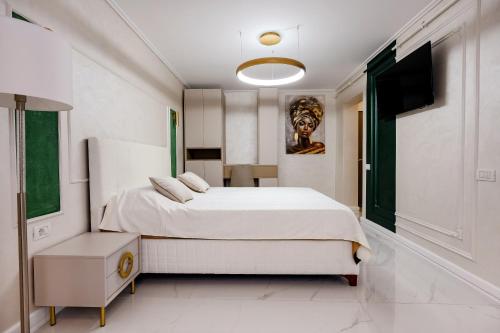 a white bedroom with a bed and a television at Luxury House in Drăgăşani