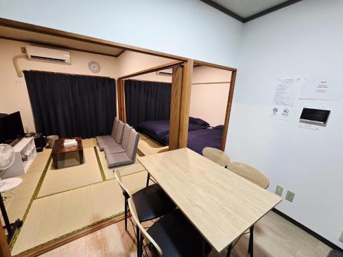 a room with a table and chairs and a bedroom at ZEUS choice FUKUOKA in Fukuoka