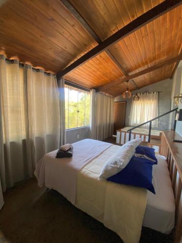 a bedroom with a large bed with a wooden ceiling at Chalés Lavras de Minas - Belém in Lavras Novas