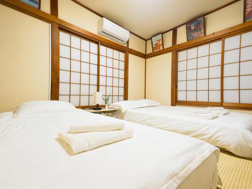 two white beds in a room with windows at 7時IN19時OUT # 池袋駅でのお迎えあり # ヴィラ一軒家貸切 # 駅近8分 # 池袋駅10分 # 上野駅13分 # 7 00 IN19 00 OUT # Pick up Ikebukuro # Whole villa rental # 8 min to station # 10 min to Ikebukuro # 13 min to Ueno in Tokyo