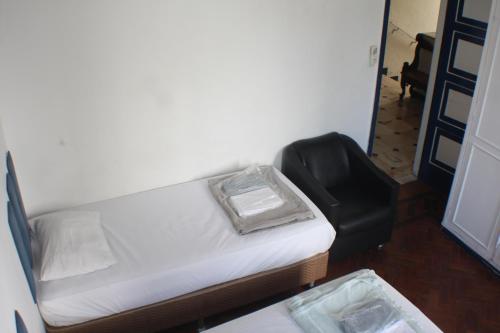 a small bed and a black chair in a room at Farfalla Guest House in Rio de Janeiro