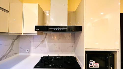 a black stove top in a kitchen with white cabinets at Skyline Hotel Apartments-Elysium Tower Facing Centaurus Mall Islamabad in Islamabad