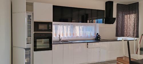 a kitchen with white cabinets and black appliances at Virág Vendégház Balatonszárszó in Balatonszárszó