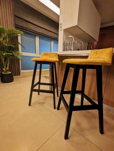 a kitchen with two bar stools in front of a counter at Skyline Hotel Apartments-Elysium Tower Facing Centaurus Mall Islamabad in Islamabad