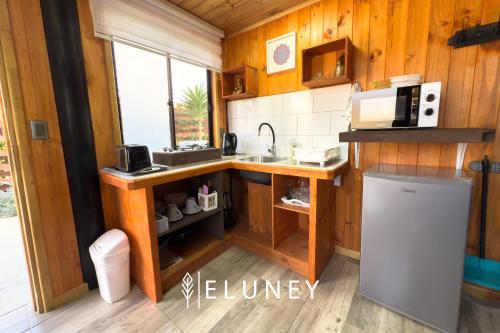 a small kitchen with a sink and a refrigerator at ELUNEY Pichilemu in Pichilemu