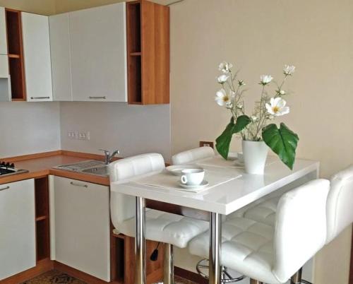 a kitchen with a table with white chairs and flowers at Wohnung mit Gemeinschaftspool in Tignale