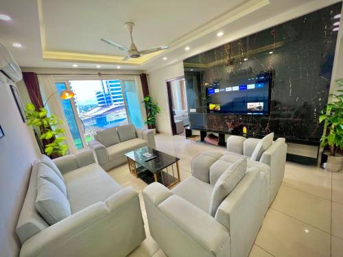 a living room with white furniture and a flat screen tv at Skyline Hotel Apartments-Elysium Tower Facing Centaurus Mall Islamabad in Islamabad