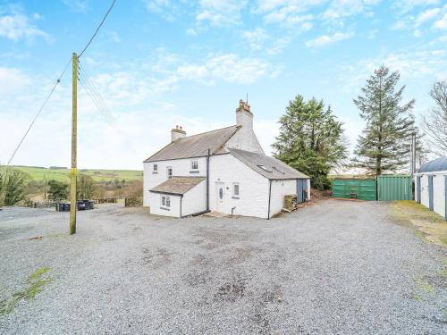 a white house sitting on top of a gravel driveway at Airyhemming Farm in Glenluce