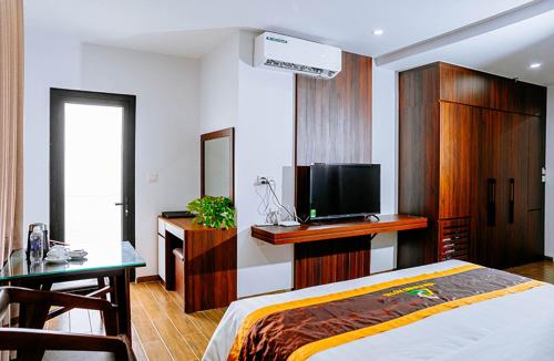 a bedroom with a bed and a desk and a tv at Văn Lâm Hotel 