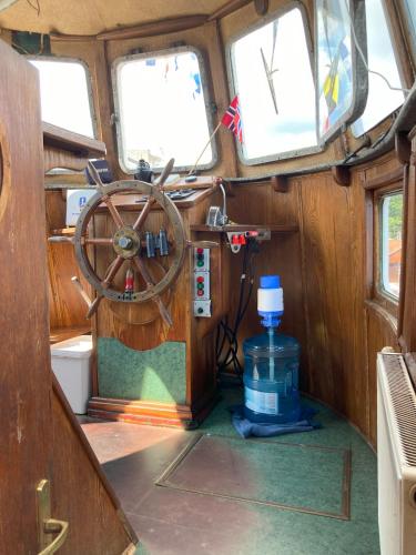 a boat with a steering wheel and a bottle of water at LOTOSS ex ice class Pilot ship in Engure