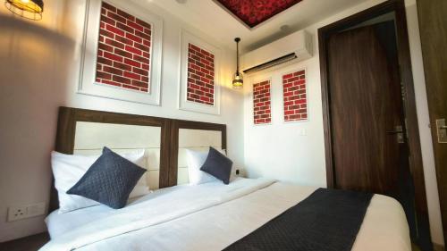 a bedroom with a bed with white sheets and blue pillows at Hotel HomeAste 001 Near Yashobhoomi Convention Center in New Delhi
