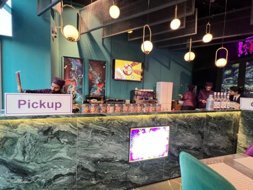 a restaurant with a counter with a person behind the counter at Skyline Hotel Apartments-Elysium Tower Facing Centaurus Mall Islamabad in Islamabad