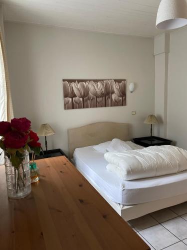 ein Schlafzimmer mit einem weißen Bett und einer Vase aus Rosen in der Unterkunft Le Mont Joly & Les 4 Têtes in Sallanches