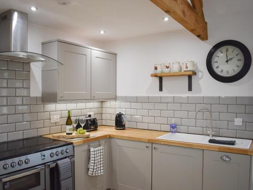 a kitchen with a sink and a clock on the wall at Stabal Eithinog in Pen-y-groes