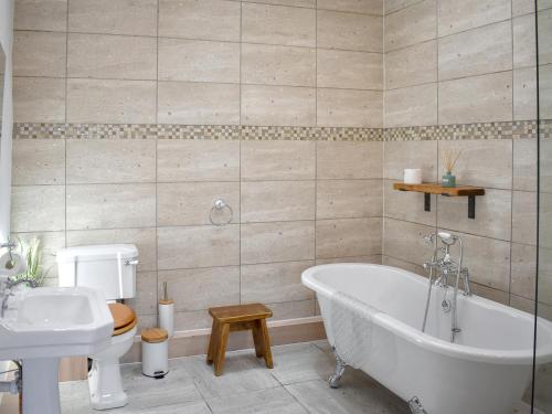 a bathroom with a tub and a toilet and a sink at Stabal Eithinog in Pen-y-groes