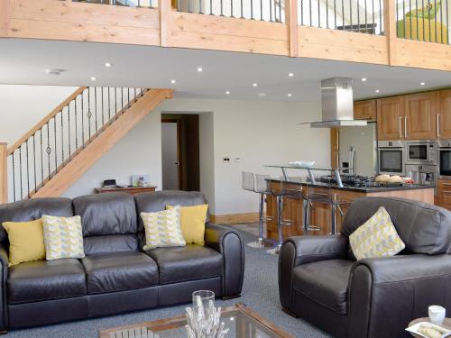 a living room with two leather couches and a kitchen at Holmegarth in Plumbland
