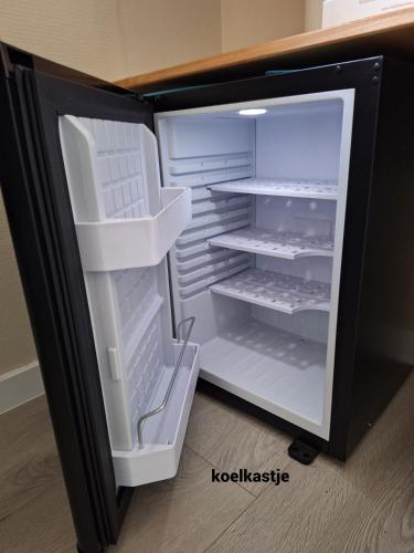 an empty refrigerator with its door open in a room at 22up Bed & Koffie in Den Burg
