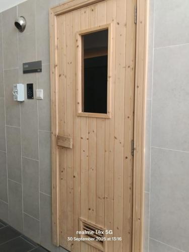 a wooden door with a window in a bathroom at Alinea BlueView Suites in Shah Alam