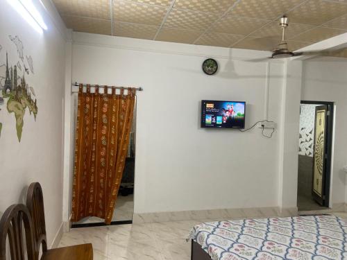 a bedroom with a bed and a tv on the wall at dibrugarh guest house in Dibrugarh