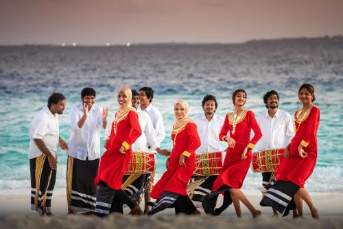 a group of people walking on the beach at Swarn by Hawks Hotels Kamadhoo Baa Atoll in Baa Atoll