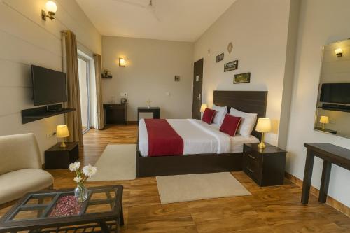 a hotel room with a bed and a living room at Pearl Grand Boutique Cottage in Omaxe Anandam Vrindavan - #premium AC rooms with balcony #big parking #lift #garden #peaceful area #near prem mandir #property of the year #most awarded in Vrindāvan