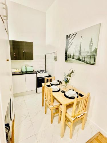 a kitchen with a wooden table and chairs at One Bedroom Flat A in Kentish Town in London