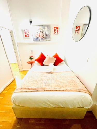 a bedroom with a bed with red pillows and a mirror at One Bedroom Flat A in Kentish Town in London