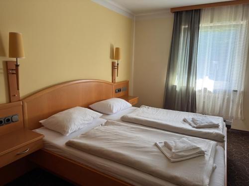 two twin beds in a hotel room with a window at LuCA Hotel in Bodenmais