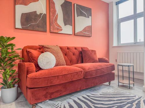 レスターにあるStylish 2 Bed 2 Bath Apartment - Sleeps 5 - 3 Mins to St Margarets Station & Highcross - Free Parkingのオレンジ色の壁のリビングルーム(赤いソファ付)