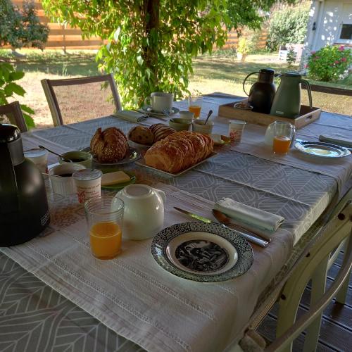 a table with a breakfast of croissants and orange juice at La Gisière, Chambres d'hôtes in Challans