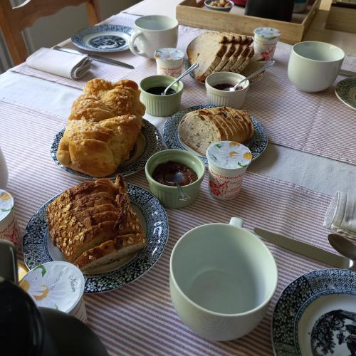 a table with plates of pastries and bowls of jam at La Gisière, Chambres d'hôtes in Challans
