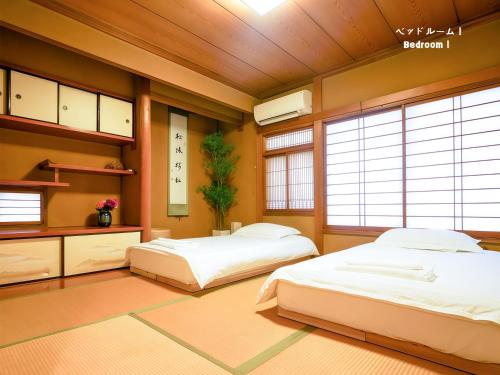 two beds in a room with two windows at 7時IN19時OUT相談可 # 池袋王子赤羽駅無料送迎 # 上野駅14分 # 一棟貸し # 2LDK2LDK # 7 00 IN19 00 OUT upon request # Free pick-up at Ikebukuro, Oji, and Akabane Stations # 14 min to Ueno # Whole house rental # 2LDK2LDK in Tokyo