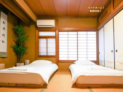 two beds in a room with two windows at 7時IN19時OUT # 池袋王子赤羽駅無料送迎 # 上野駅14分 # 一棟貸し # 2LDK2LDK # 最大24人 # 7 00 IN19 00 OUT # Free pick-up at Ikebukuro, Oji, and Akabane Stations # 14 min to Ueno # Whole house rental # 2LDK2LDK # Max 24 in Tokyo