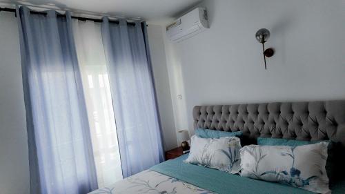 a bedroom with a large bed with blue curtains at AVELORA HOMES Paje in Fumba