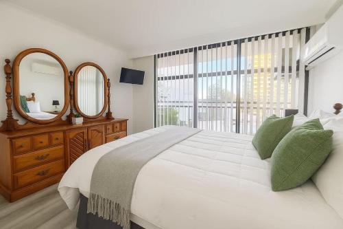 Un dormitorio con una gran cama blanca y un espejo. en 1BR Apartment Heated pool, en Gold Coast