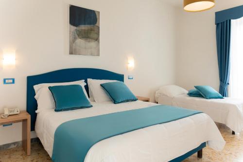a bedroom with two beds with blue pillows at Hotel Britannia in Sorrento