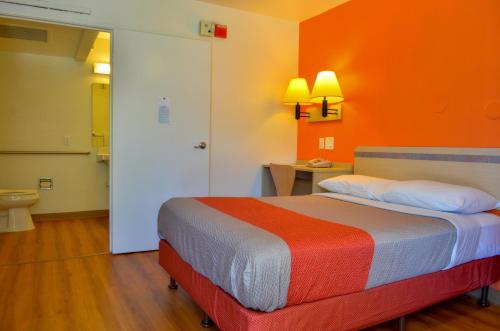 Habitación con cama con pared de color naranja en Motel 6-Santa Nella, CA - Los Banos - Interstate 5, en Santa Nella