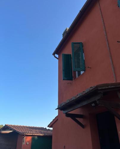 a red building with green shutters on it at La Piastraia in Parlascio